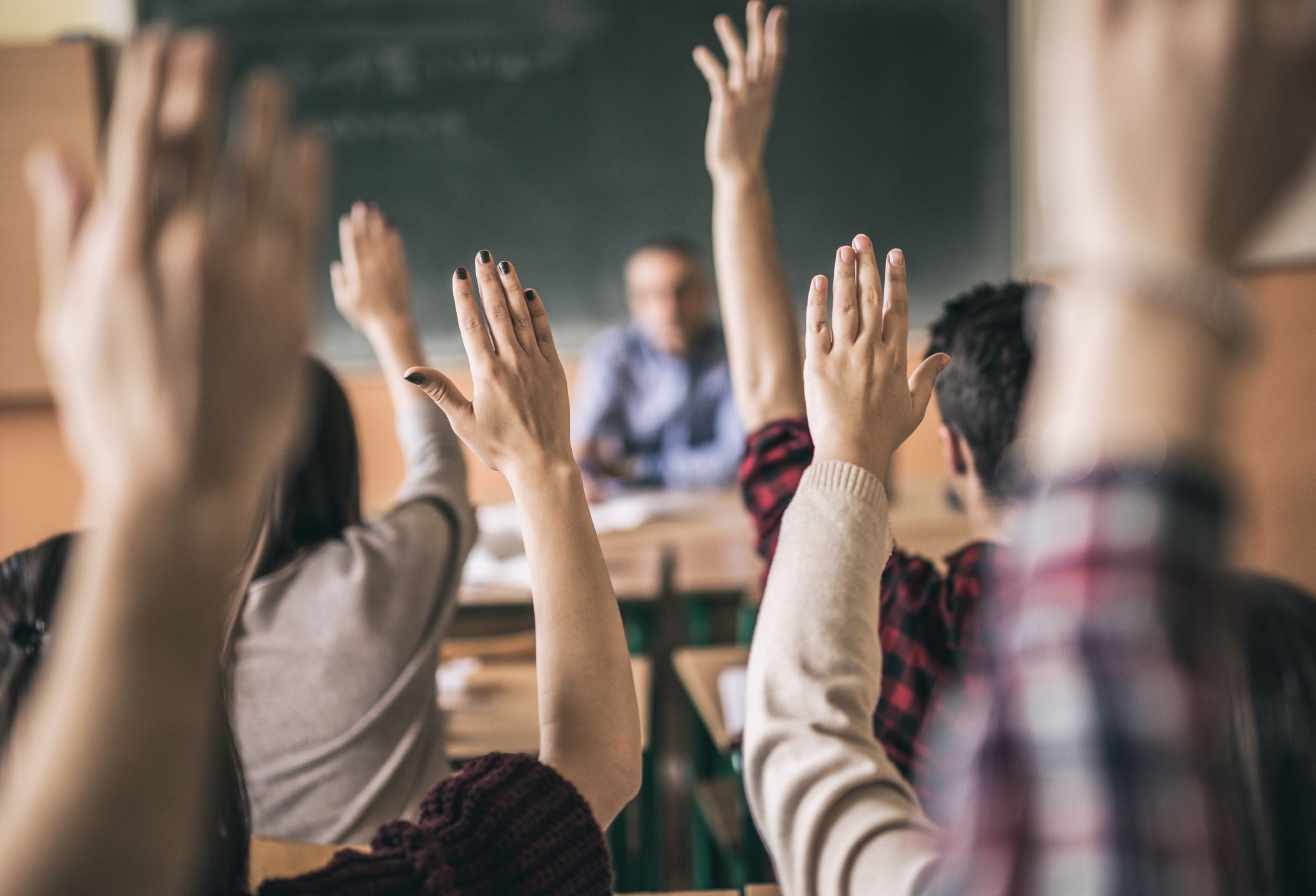People raise their hands in a classroom