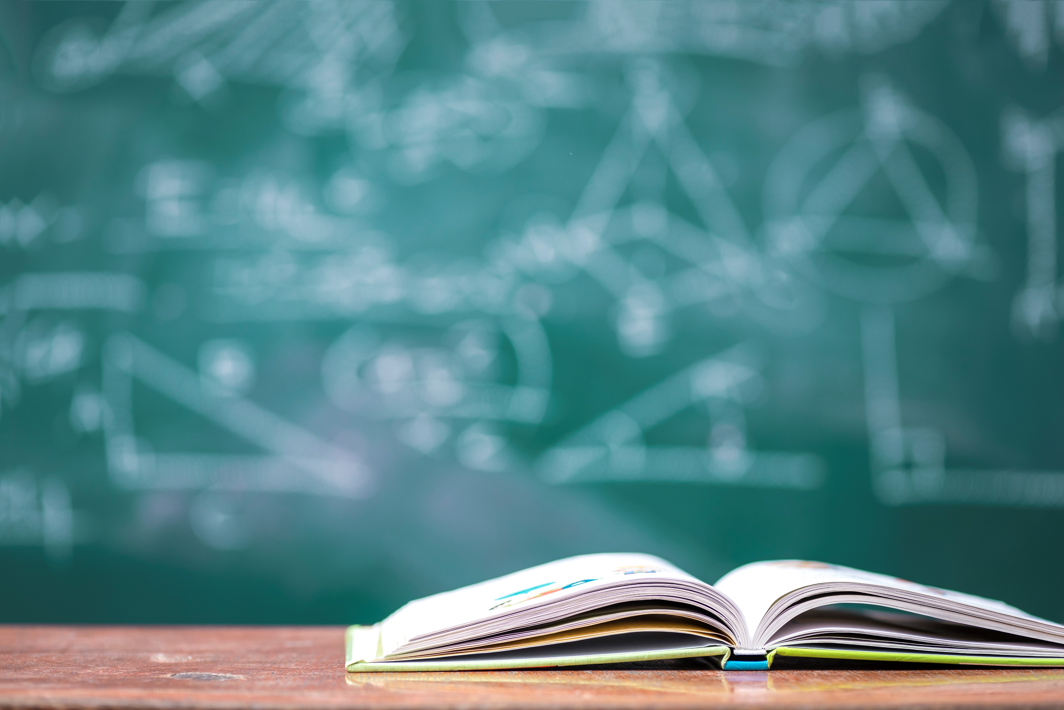 An open book in front of a science classroom board